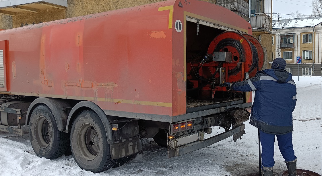 Каналопромывочная машина и работник прочищают засор в канализационной системе в Аргуне